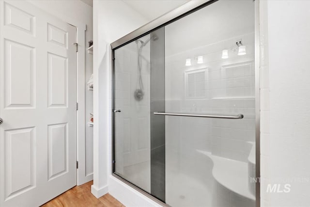 full bath with a stall shower and wood finished floors