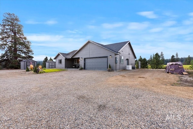 view of front of property featuring an outbuilding, central AC unit, an attached garage, driveway, and a shed