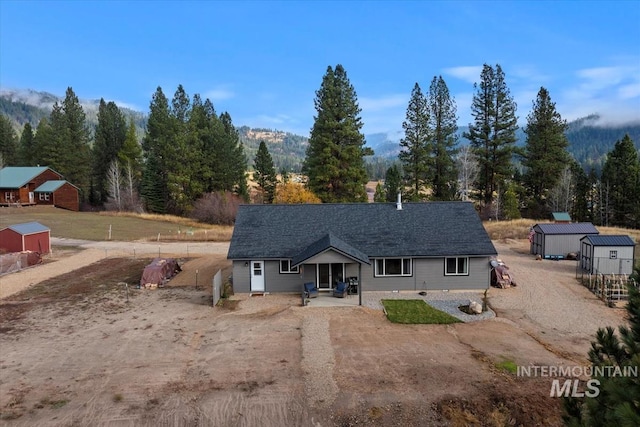 view of front of house featuring an outbuilding, driveway, a patio, and a storage unit