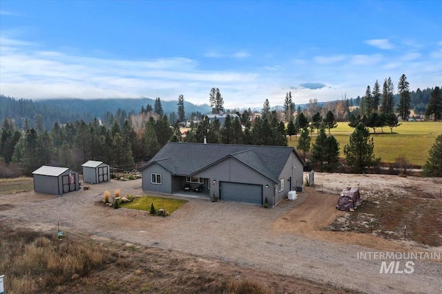 view of front of property with a storage shed, driveway, an attached garage, and an outbuilding