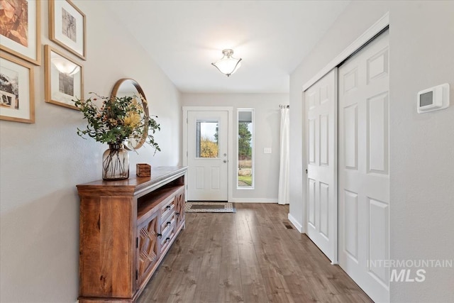 doorway featuring baseboards and wood finished floors