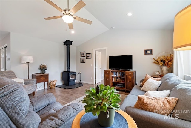 living area with a ceiling fan, lofted ceiling, wood finished floors, a wood stove, and recessed lighting