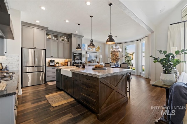 kitchen with pendant lighting, decorative backsplash, sink, stainless steel appliances, and ventilation hood