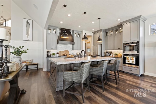 kitchen with hanging light fixtures, dark hardwood / wood-style flooring, stainless steel refrigerator, and gray cabinetry