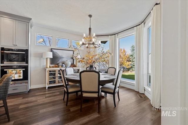 dining room with dark hardwood / wood-style floors, a wealth of natural light, and an inviting chandelier