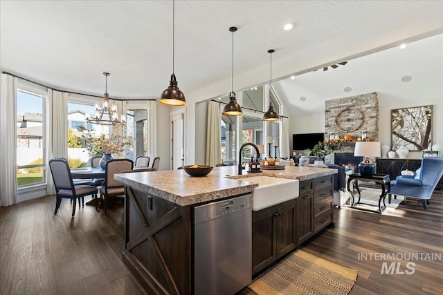 kitchen featuring pendant lighting, sink, vaulted ceiling, stainless steel dishwasher, and a center island with sink