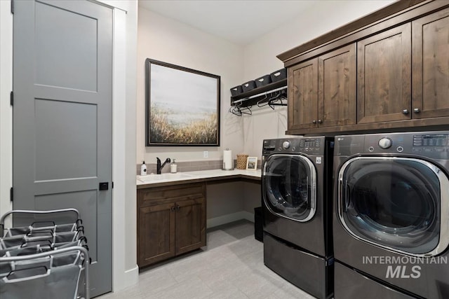 clothes washing area featuring sink, washer and dryer, and cabinets