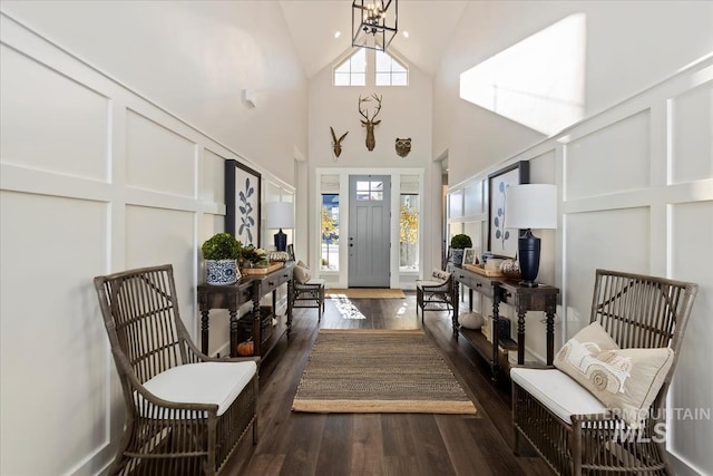 foyer entrance with an inviting chandelier, dark hardwood / wood-style flooring, and a towering ceiling