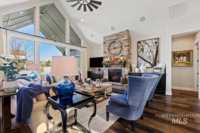 living room with high vaulted ceiling, ceiling fan, dark wood-type flooring, and a stone fireplace