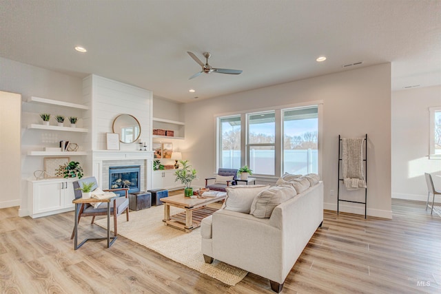 living room with light wood finished floors, a fireplace, visible vents, and a wealth of natural light