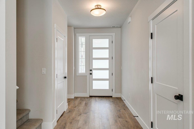 entrance foyer featuring light wood-type flooring, baseboards, stairs, and visible vents