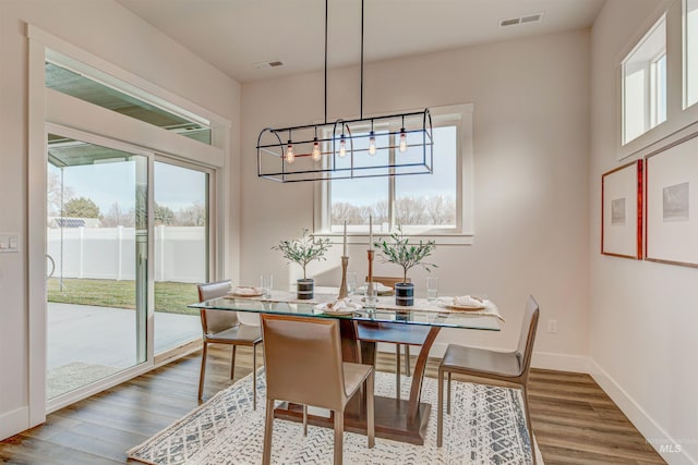 dining area with baseboards, visible vents, a chandelier, and wood finished floors