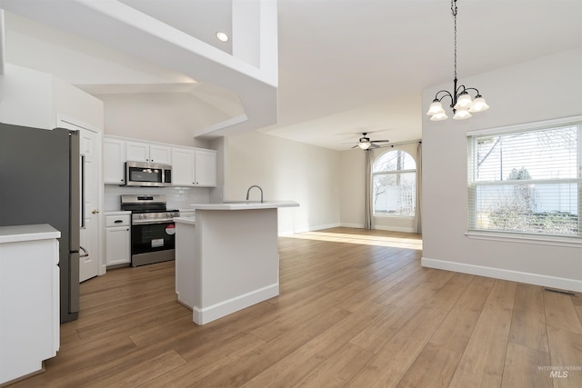 kitchen featuring white cabinetry, light hardwood / wood-style flooring, hanging light fixtures, appliances with stainless steel finishes, and ceiling fan with notable chandelier