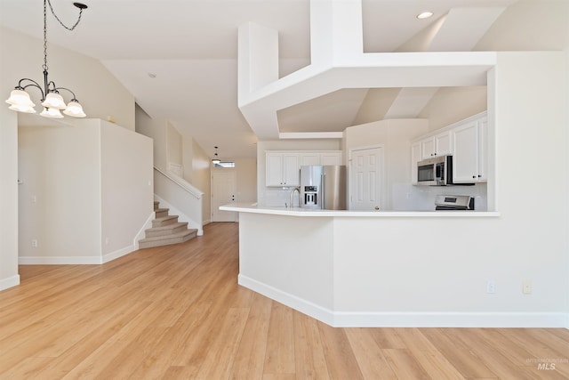 kitchen featuring backsplash, a notable chandelier, appliances with stainless steel finishes, high vaulted ceiling, and white cabinets