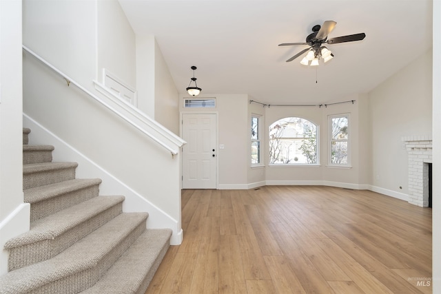 entrance foyer with ceiling fan, light hardwood / wood-style flooring, and a brick fireplace