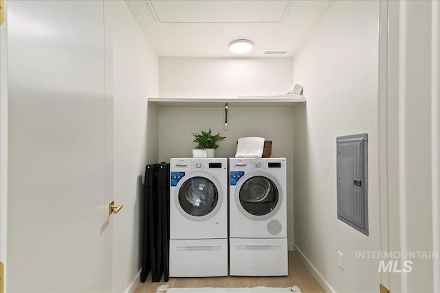 laundry room featuring washer and clothes dryer, light wood-type flooring, and electric panel