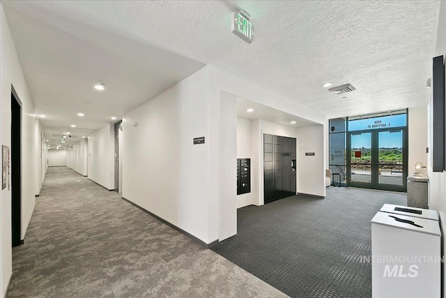 hall featuring dark colored carpet, mail boxes, a textured ceiling, and elevator