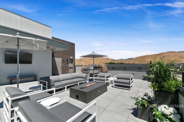 view of patio with a mountain view and an outdoor living space with a fire pit