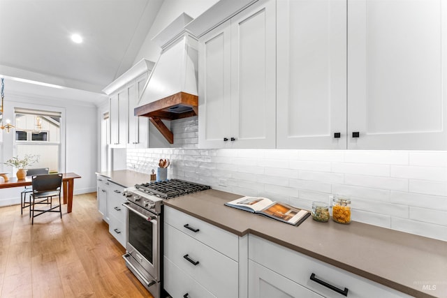 kitchen with high end stove, custom range hood, light wood-style flooring, and white cabinets