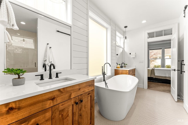 bathroom with ensuite bath, a freestanding bath, a stall shower, vanity, and recessed lighting