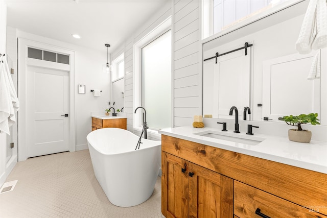 bathroom featuring recessed lighting, a sink, a freestanding bath, and two vanities