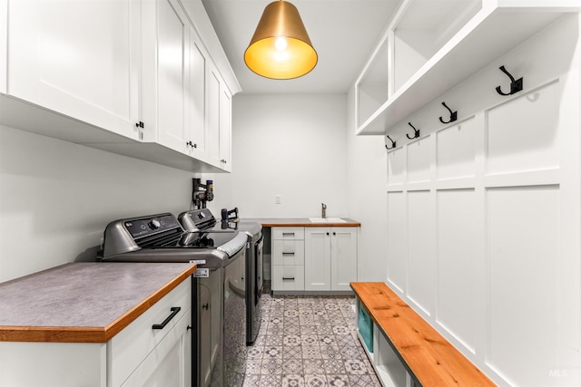 laundry area with cabinet space, washing machine and dryer, a sink, and light floors