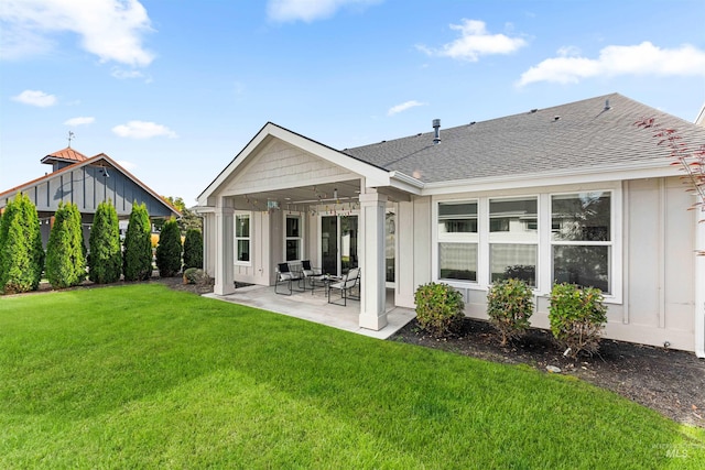 rear view of property with board and batten siding, a patio, roof with shingles, and a lawn