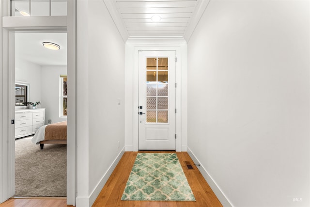 entryway with baseboards, ornamental molding, light wood-style flooring, and visible vents