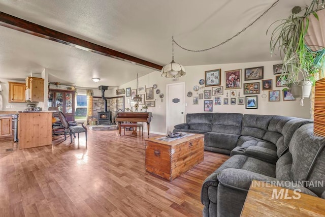 living room featuring a wood stove, wood-type flooring, and vaulted ceiling with beams