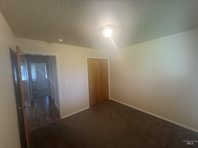 2451 W Park Stone Dr, Meridian, ID 83646 - unfurnished bedroom with a textured ceiling, baseboards, a closet, and dark colored carpet