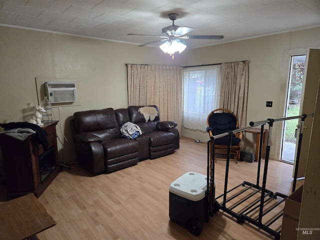 living room with a wall mounted air conditioner, a wealth of natural light, wood-type flooring, and ornamental molding