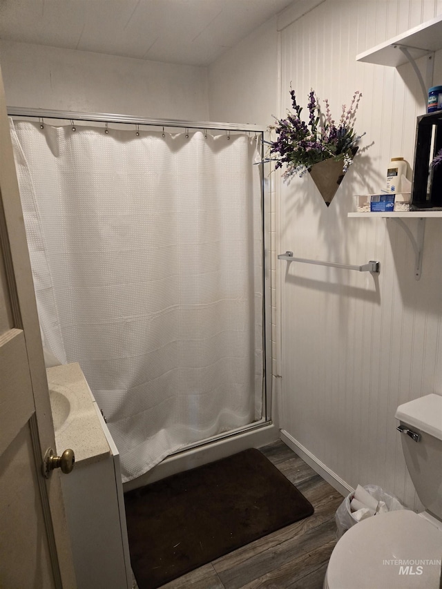 bathroom with hardwood / wood-style floors, toilet, vanity, and walk in shower