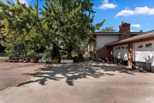 20035 Franklin Rd, Nampa, ID 83687 - view of side of home featuring concrete driveway, an attached garage, a chimney, and brick siding