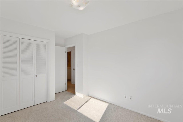 unfurnished bedroom with light colored carpet and a closet