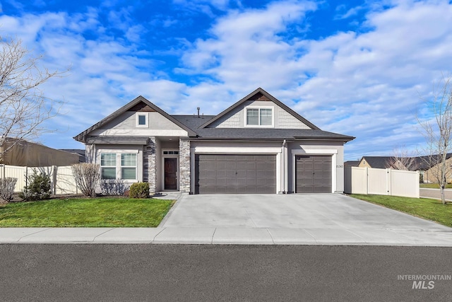 view of front facade featuring an attached garage, fence, concrete driveway, stone siding, and a front lawn