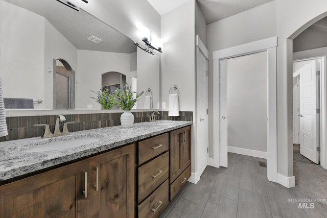 bathroom with double vanity, an enclosed shower, baseboards, and a sink