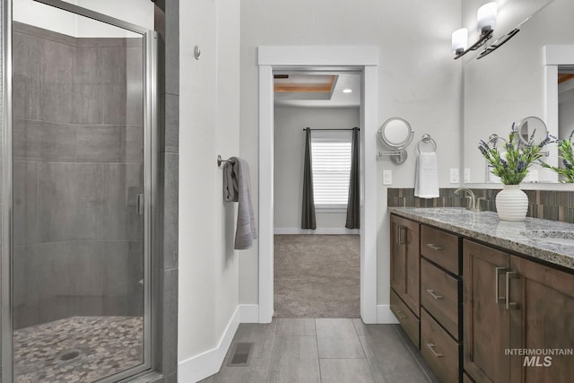 full bathroom featuring double vanity, a stall shower, and a sink