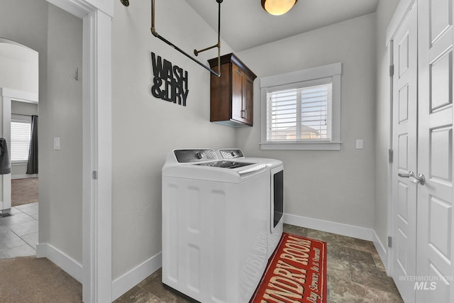 laundry room with arched walkways, a wealth of natural light, washing machine and dryer, and cabinet space