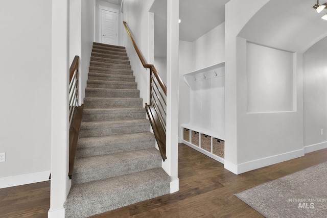 stairway featuring arched walkways, wood finished floors, and baseboards