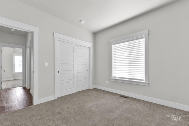 unfurnished bedroom with carpet floors, visible vents, baseboards, and a closet