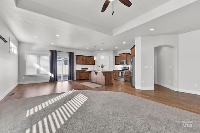 unfurnished living room with dark wood-type flooring, arched walkways, and plenty of natural light