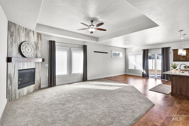 unfurnished living room featuring a raised ceiling, a large fireplace, and a textured ceiling