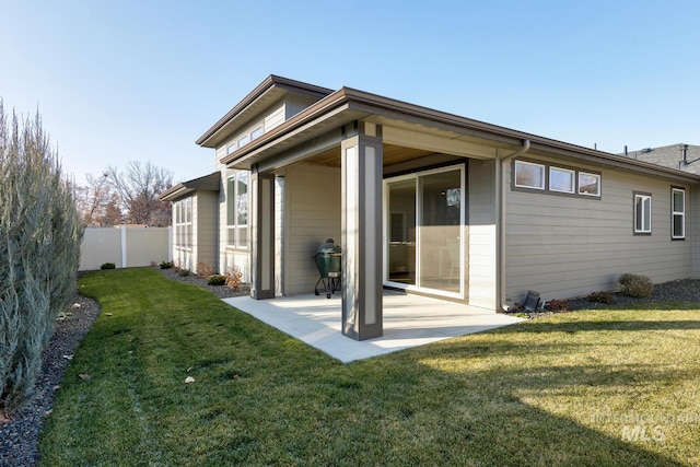 back of house with a patio and a lawn