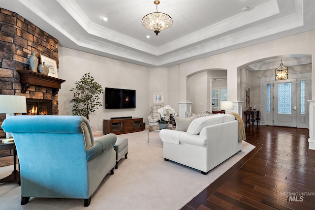 724 E Lakebrook Ln, Eagle, ID 83616 - living room featuring arched walkways, a raised ceiling, a chandelier, a stone fireplace, and ornamental molding