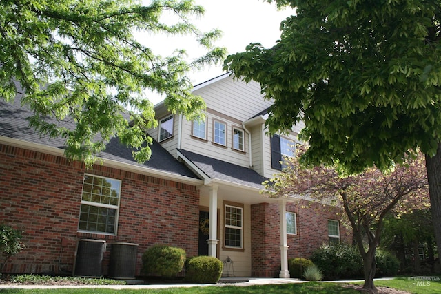 view of front facade with cooling unit and brick siding