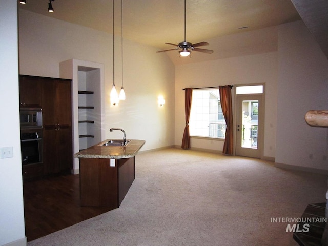 kitchen featuring stainless steel microwave, a sink, oven, carpet, and ceiling fan