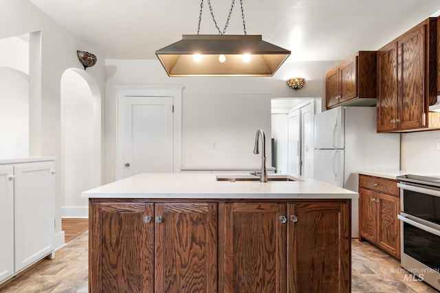 kitchen with double oven range, a center island with sink, a sink, and stone finish flooring