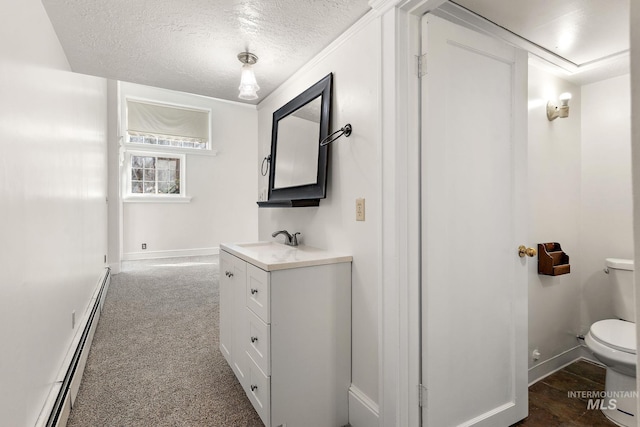 bathroom with a textured ceiling, toilet, a baseboard heating unit, vanity, and baseboards