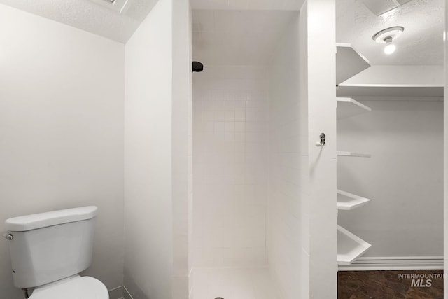 full bathroom featuring a stall shower, baseboards, a textured ceiling, and toilet