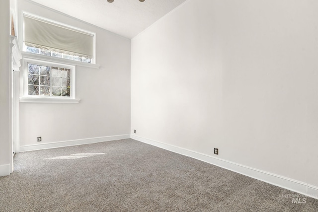 empty room featuring lofted ceiling, carpet flooring, and baseboards